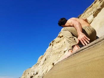 Low angle view of man relaxing on rock