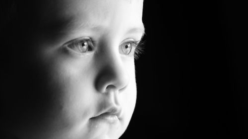 Close-up of baby boy against black background