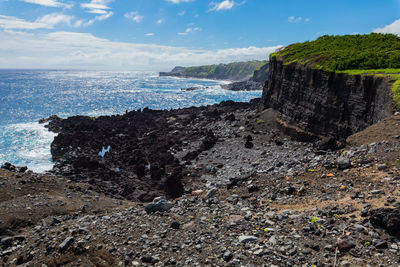 Rock formation on beach against sky