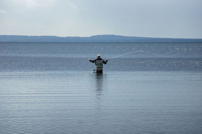 Rear view of man standing on boat at sea