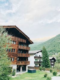 House amidst trees and buildings against sky