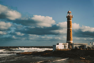 Lighthouse by sea against sky