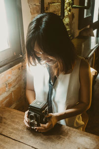 Woman holding camera at home