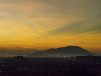 Silhouette buildings in city against romantic sky at sunset