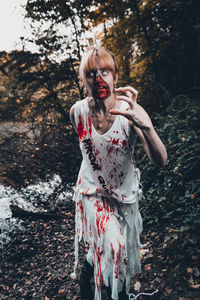 Woman with zipper and face paint running against tree