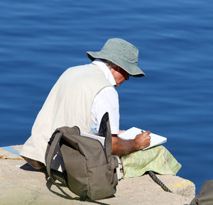 Man writing in book while sitting at beach