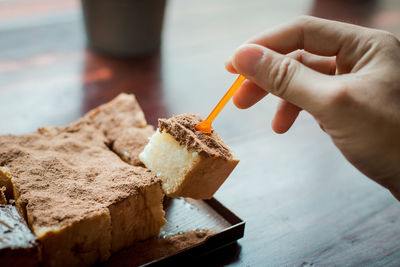 Close-up of hand holding ice cream on table