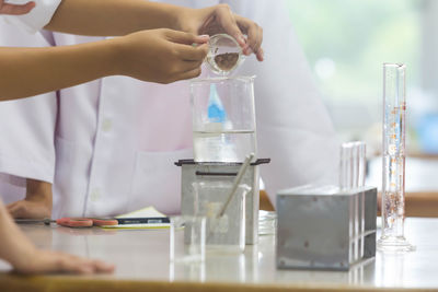 Midsection of scientists performing experiment at laboratory