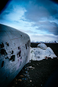 Abandoned military airplane at beach against cloudy sky during winter