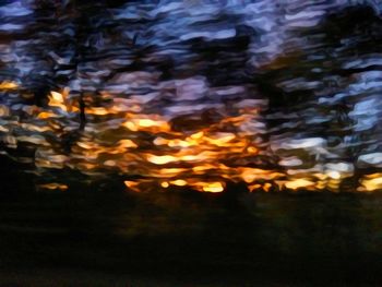 Defocused image of illuminated tree against sky at night