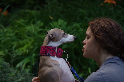 Dog looking at woman against plants