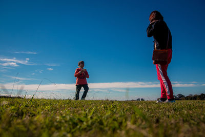 Mother and son with model airplane on grass against sky