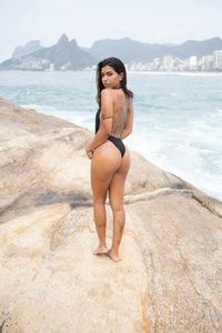 Portrait of young woman in bikini standing on beach