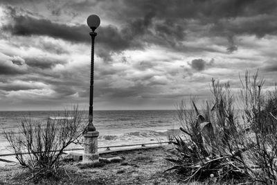 Street light by sea against sky