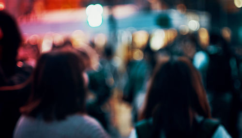 Defocused image of women standing in city at night