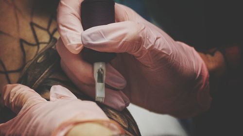 Cropped hands of person making tattoo