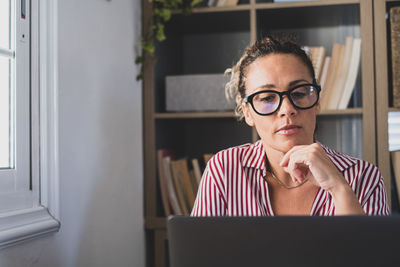 Portrait of young woman using laptop at home