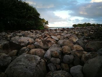 Rocks by sea against sky during sunset
