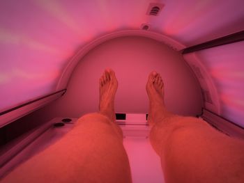 Low section of man lying down on tanning bed