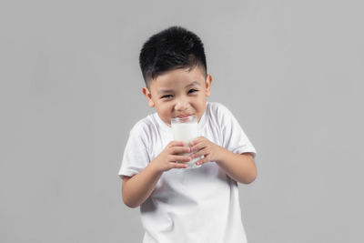 Full length of a boy drinking water against white background