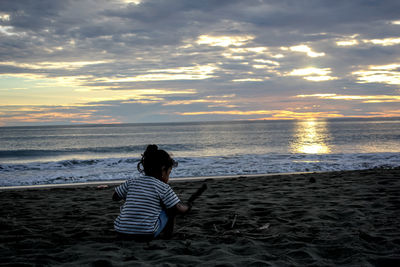 Rear view of woman sitting on beach