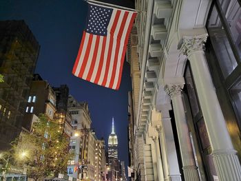 Low angle view of illuminated flag amidst buildings in city at night