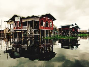 Stilt houses by lake against sky