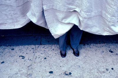 Low section of man standing behind white curtain