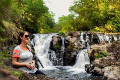 Woman standing on waterfall in forest