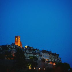Illuminated buildings against clear blue sky