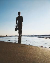 Full length of woman standing at beach against clear sky