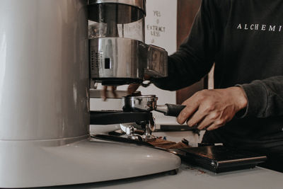 Midsection of man preparing coffee in cafe