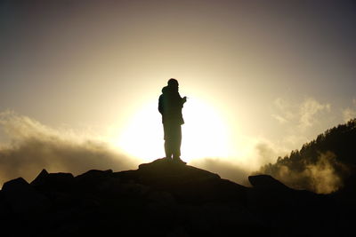 The silhouette of a man smoking, looking at the sunset in a base camp in dharamsala