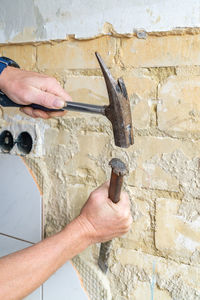 Worker hammering old wall