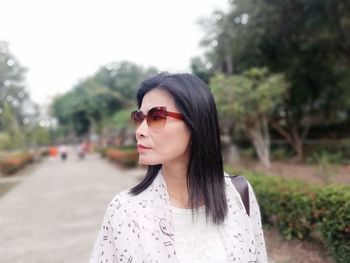 Woman wearing sunglasses standing trees at park