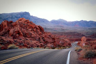 Scenic view of road by mountains against sky