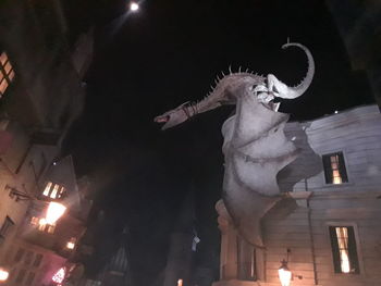 Low angle view of statue against illuminated building at night