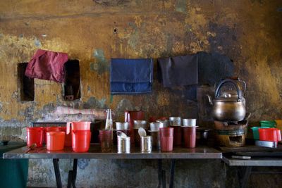 Clothes drying on clothesline with kitchen utensils on table against wall