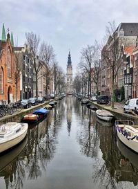 Boats moored in canal amidst buildings in city