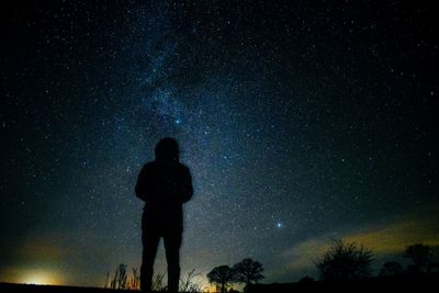 Silhouette man standing against star field at night
