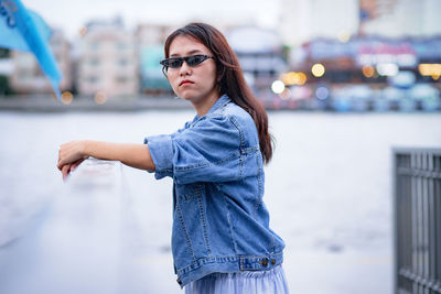 Young woman wearing sunglasses standing against built structure