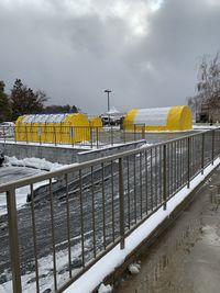 Snow covered railing against sky during winter