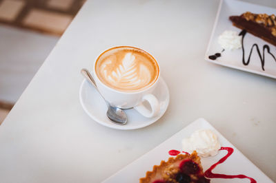 High angle view of cappuccino with pastry served on table