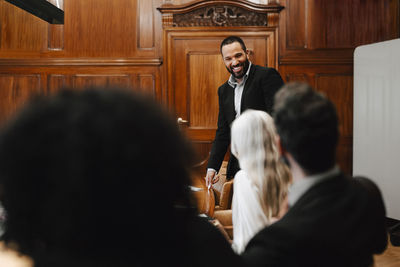 Smiling businessman discussing with colleagues during meeting in board room