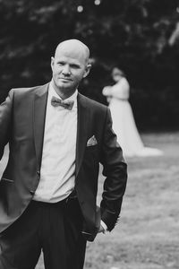 Portrait of completely bald man wearing suit while standing at park