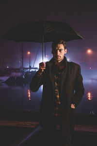 Portrait of young man with umbrella at night