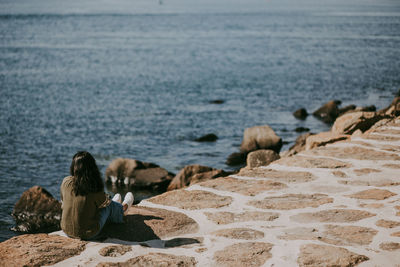 Woman sitting on rock by sea