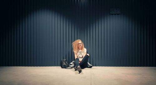 Full length of woman sitting on chair against wall