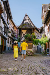 Rear view of people walking on street amidst buildings