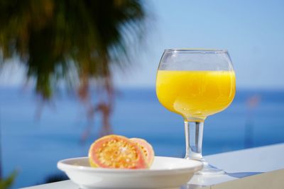 Close-up of food and drink served on retaining wall against sea